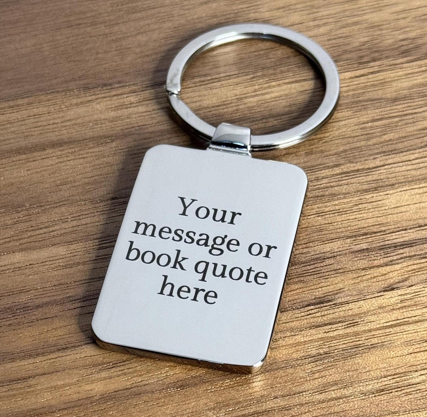 A silver keyring with an example engraved message. The message text is ‘Your message or book quote here’.