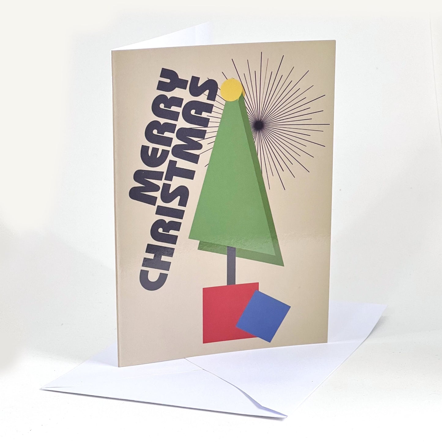 A Christmas card and envelope. The design is a geometric tree in primary colours with the word Merry Christmas positioned diagonally along the side.