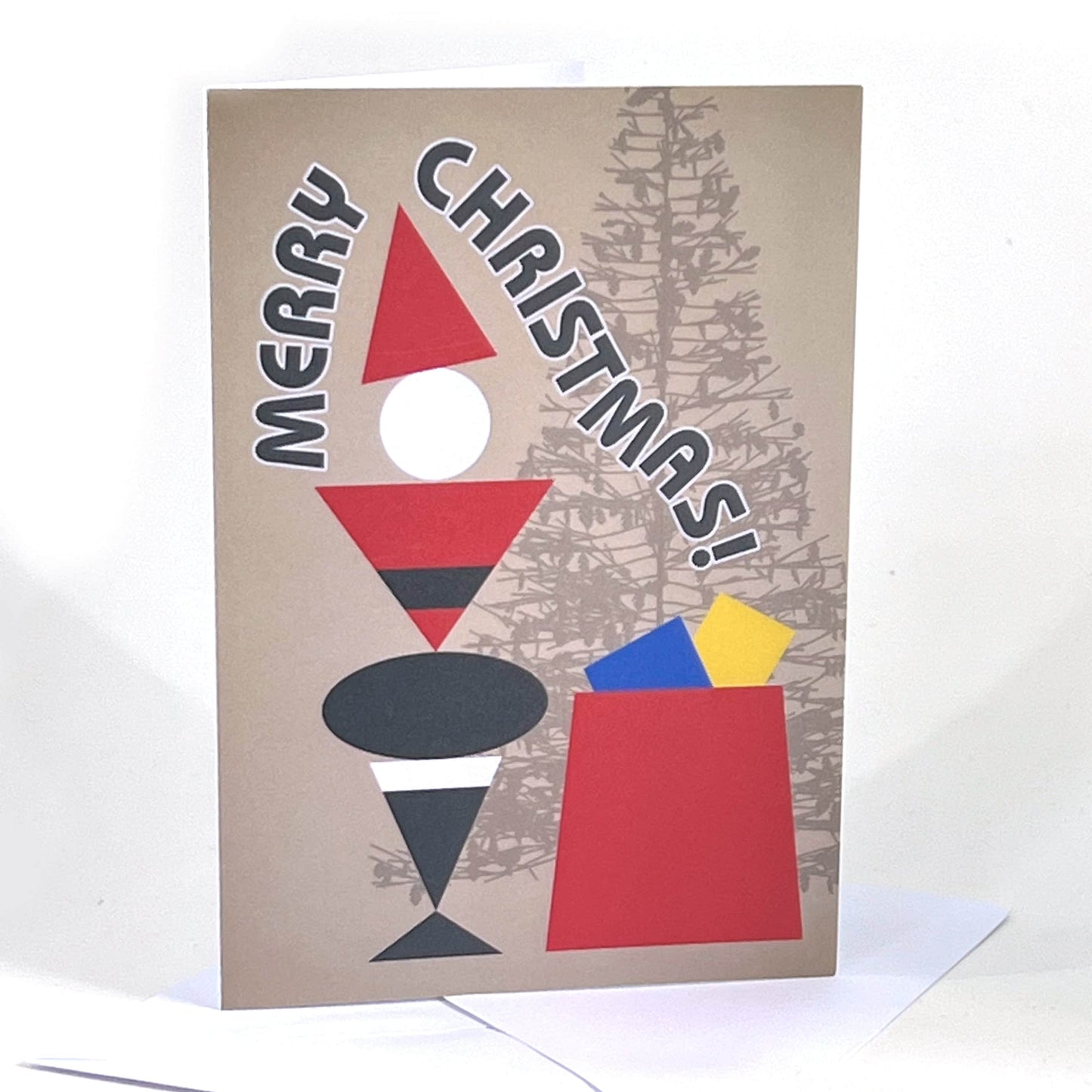 A Christmas card and envelope. The design is a geometric figure representing Father Christmas in red and black, standing next to a red sack with presents and Christmas tree in the background. The words Merry Christmas flow around the figure.